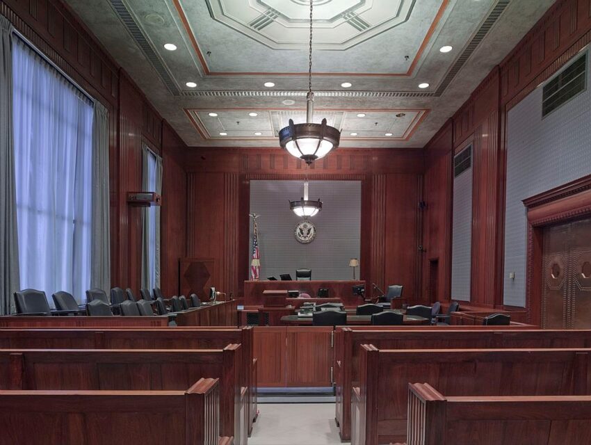 Inside of a courtroom with wooden benches and chandelier