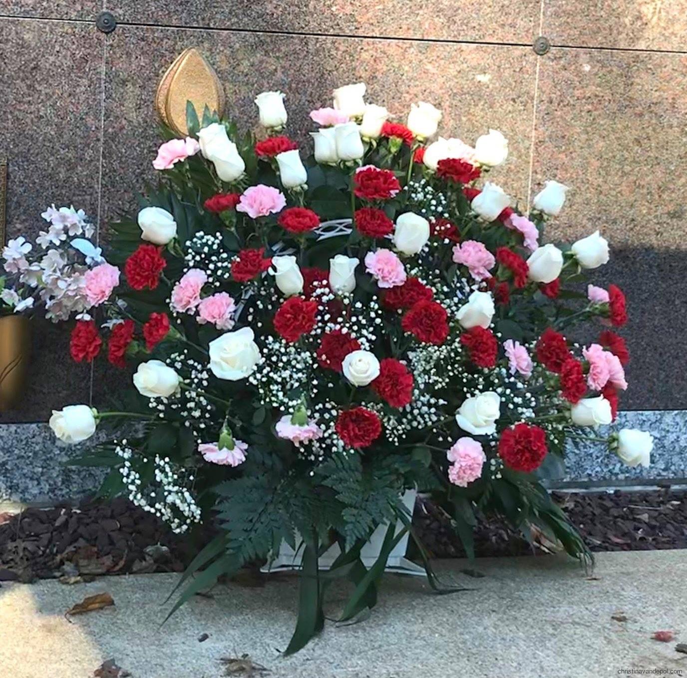 Red, pink, and white floral arrangement in front of interment crypt
