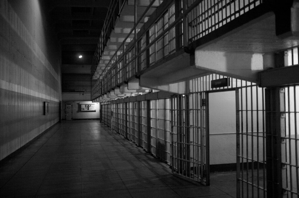 Photo of prison interior with empty cells along a long hallway. 