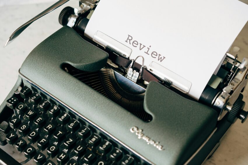 Photo of manual Olympia typewriter typing the word Review on a piece of white paper