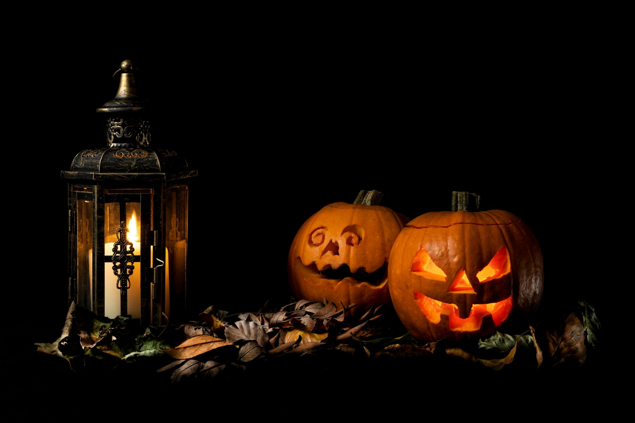 Nightime photo of lantern with two carved Halloween pumpkins